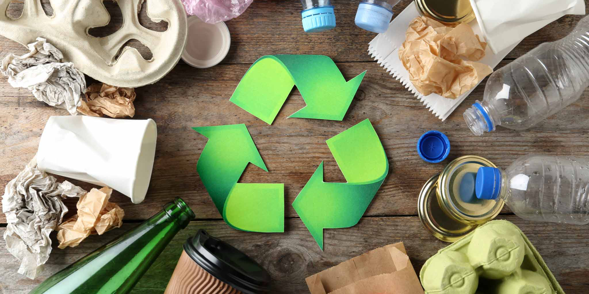Recycling symbol and different garbage on wooden background, top view